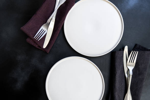 istock White craft plate, cutlery and napkin on dark stone table 1304779090