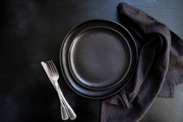 istock Black craft plate, cutlery and napkin on dark stone table 1304779606