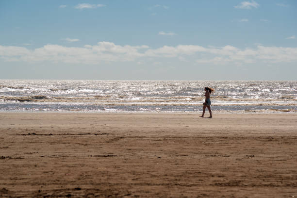 Mar del Tuyú, Buenos Aires, Argentina; December 07, 2020: A woman walking alone in the beach shore