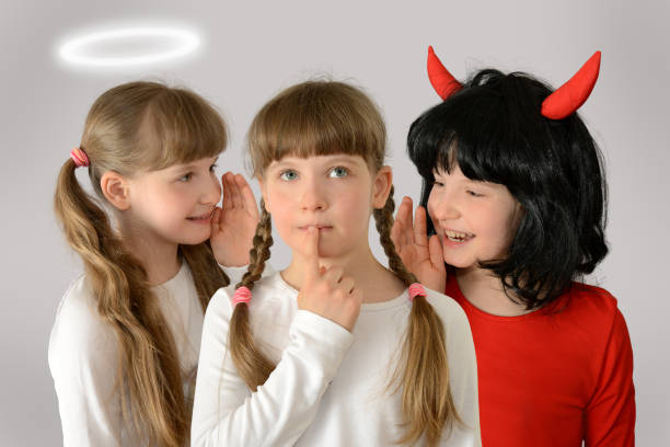 kind (kind) geven advies engel en demon fluisteren in het oor van beide kanten schadelijk, nuttig, kwaad, goed advies concept fotografie - engelenpak stockfoto's en -beelden