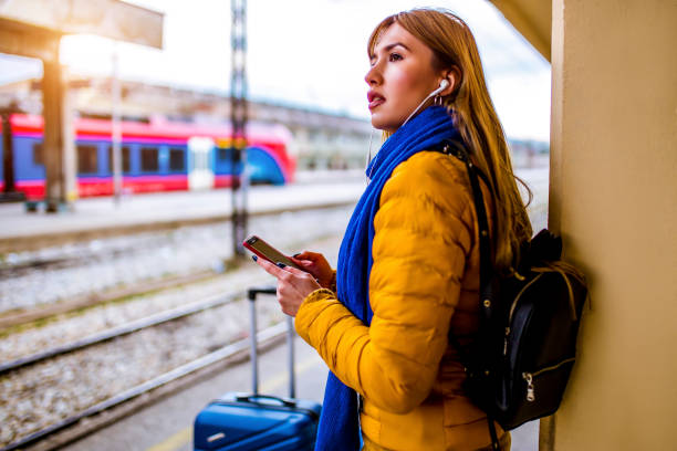 istock Young woman using her phone while waiting for train 1304781866