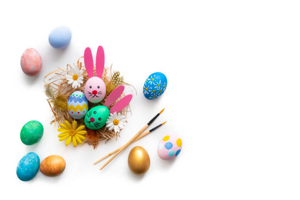 Easter Eggs on a nest hand painted with bunny face and ears and spring daisy flowers isolated on white background