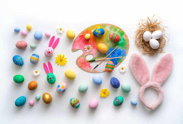 Easter Eggs hand painted with bunny face and ears, spring daisy flowers isolated on white background and a eggs nest