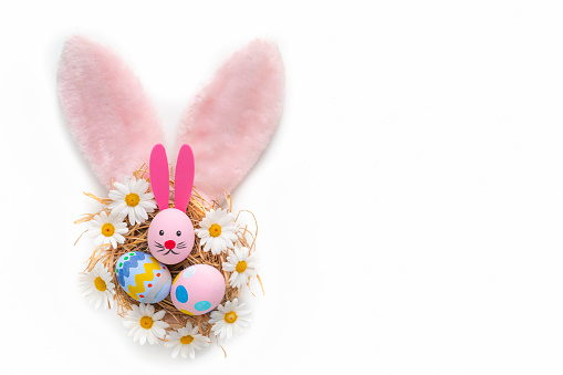 Easter Eggs with bunny face hand painted inside bunny ears pink fur with daisy spring flowers isolated on white background