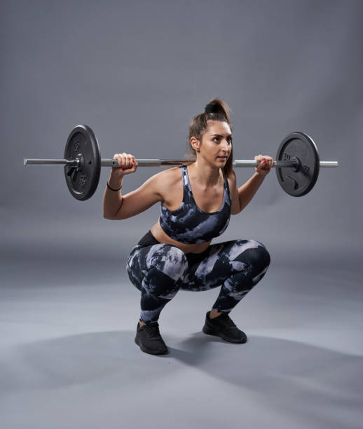istock Woman doing barbell squats 1304783296