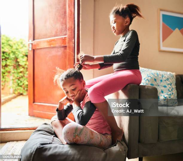 Cute little girl doing her sister's hair at home