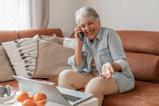 istock Senior woman talking on the phone and using laptop 1304787231