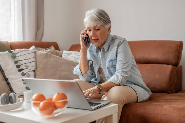Senior woman talking on the phone and using laptop