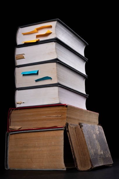A stack of books on the desk. Old extensive literary publications. Dark background.