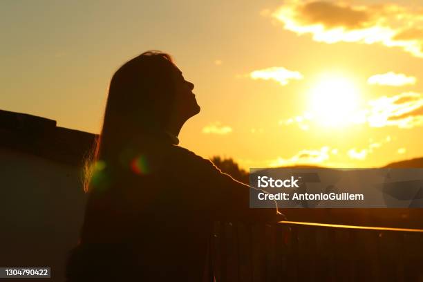 Tenant Breathing Fresh Air In A Balcony At Sunset Stock Photo - Download Image Now - Back Lit, Balcony, Sunset