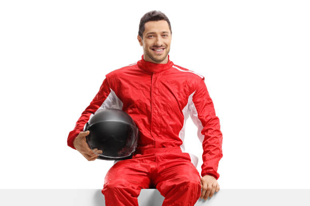 istock Car racer in a red uniform sitting on a panel holding a helmet 1304791402