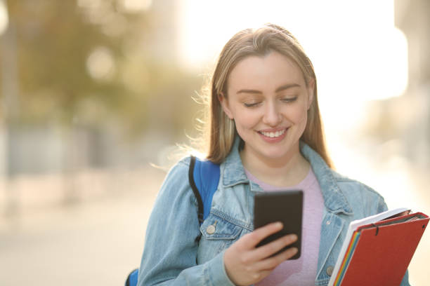 istock Happy student checking smart phone in the street 1304793512