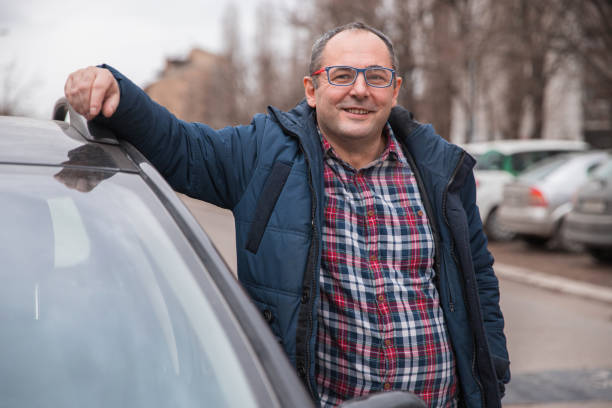 istock Cheerful man standing by a car and smiling 1304794635