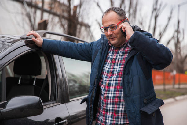 istock Joyful man leaning onto a car when having phone conversation via mobile phone 1304794654