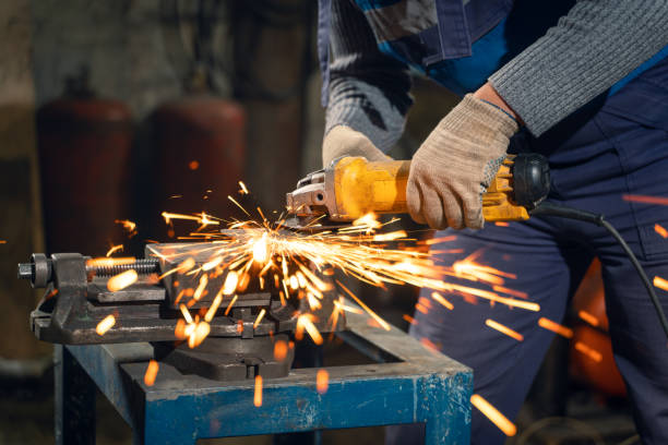 istock Locksmith in special clothes and goggles works in production. Metal processing with angle grinder. Sparks in metalworking 1304794658