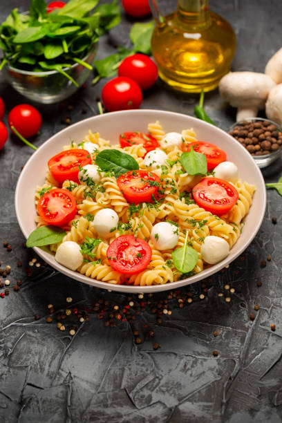 istock Fusilli Pasta with Mozzarella Cheese, Cherry Tomatoes, Basil and Herbs. Dieting Concept. Vegetarian Food Background 1304796955