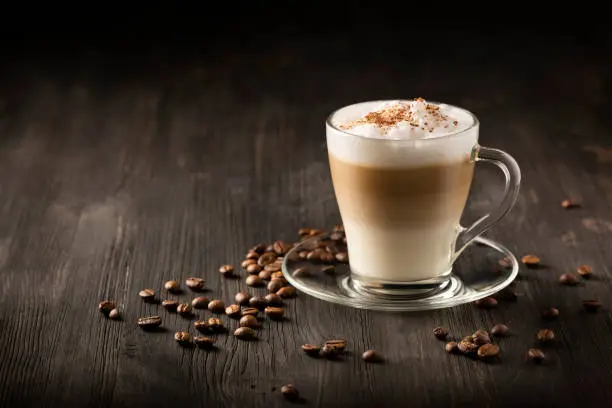 Latte Macchiato Coffee Cup on wooden table with roasted Coffee Beans