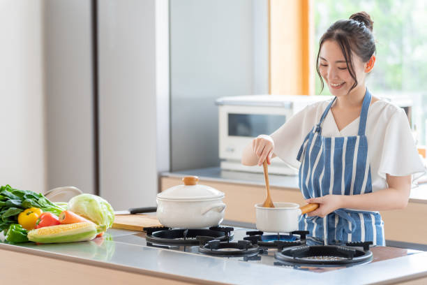 attraente donna giapponese cucina in cucina - solo giapponesi foto e immagini stock
