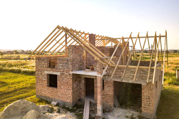 istock Unfinished brick house with wooden roof structure under construction. 1304800274