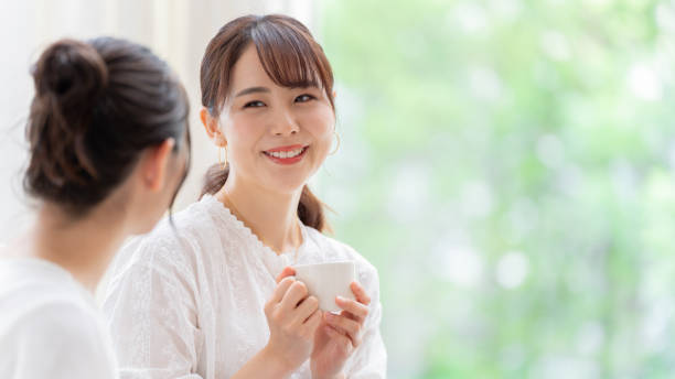 attraktive japanische frauen sprechen im wohnzimmer - japanisch sprache stock-fotos und bilder