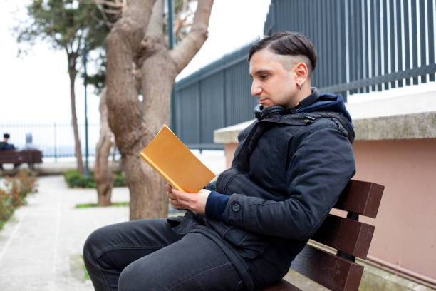 istock young man reading a book in the park 1304803879