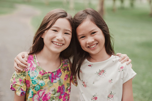 Happy and healthy mixed Asian young girls  smiling in the park, best friends and friendship and diversity concept