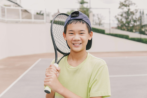 Asian preteen tween boy playing tennis,  healthy young athletes training, active wellbeing concept