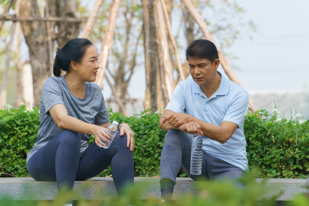 istock asian couple talking and drinking water together after exercise outdoors in park 1304810333