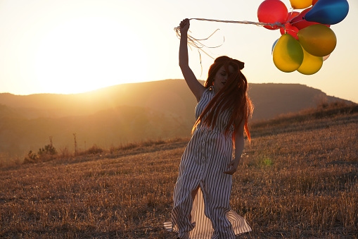 Happy woman with balloons at sunset in summer stock photo