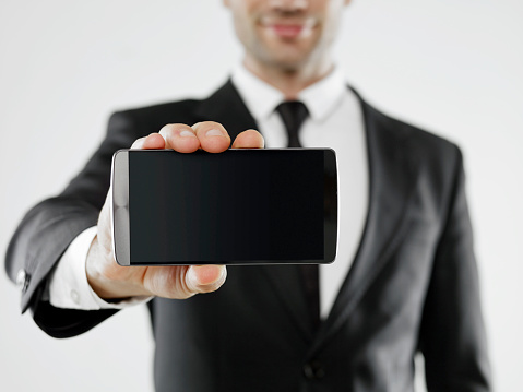 Businessman holding a mobile phone with blank display