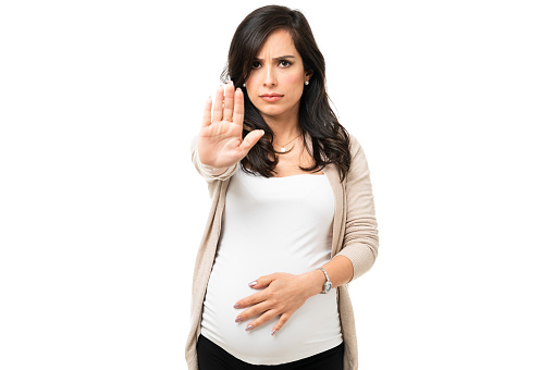 Angry pregnant woman showing a stop gesture with her hand. Upset caucasian woman feeling annoyed and having a fight with someone