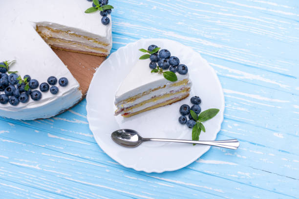 istock Appetizing cheesecake cake biscuit pillow decorated white cream blueberries and mint stands on wooden blue rustic table 1304821258