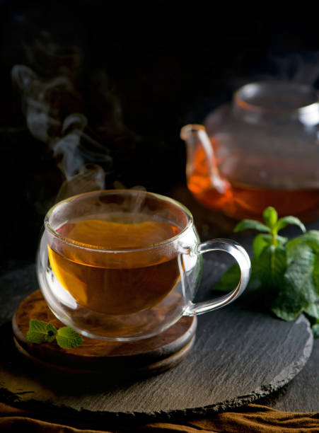 istock Tea concept, teapot with tea surrounded on wood background, tea ceremony, green tea in a transparent cup 1304822028