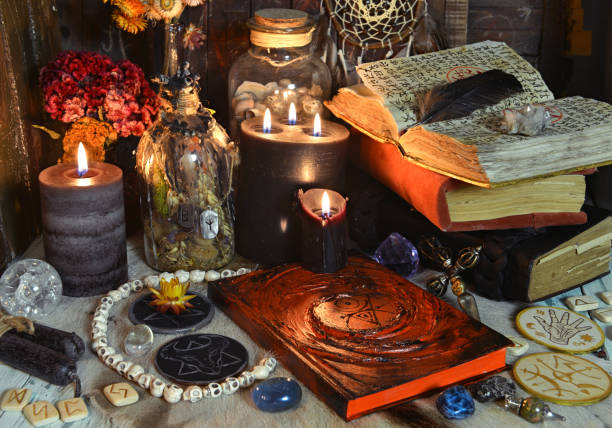 istock Still life with grimoire book of spells, burning candles, runes and ritual objects on witch table. 1304822600