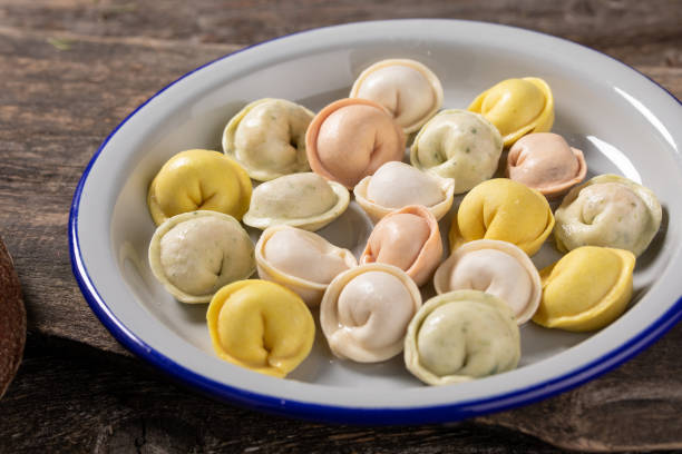 istock Traditional Russian dumplings made from multi-colored dough. Dumplings on a wooden board in an enamel plate. Cooking concept. 1304822729
