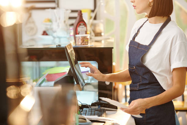 female barista using cash register Cropped image of female barista working at coffeeshop and using cash register when accepting payment or entering order detaikls cashier stock pictures, royalty-free photos & images