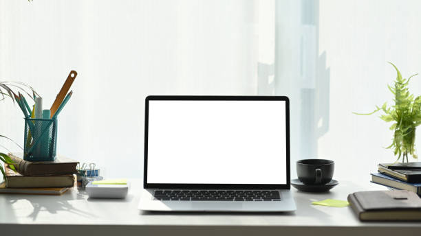 istock Front view of computer laptop, notebook, coffee cup and plant on white desk at modern home office. 1304832241