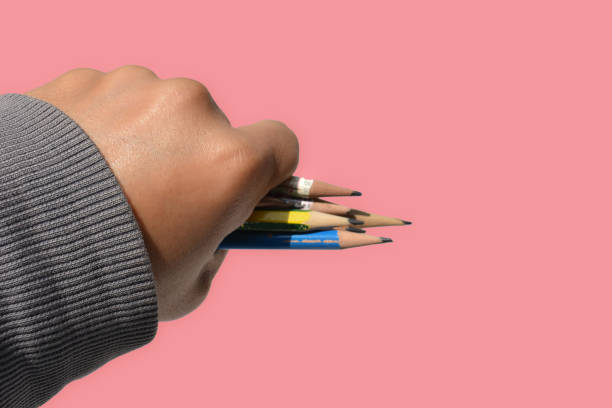 istock pencil on hand on pink background 1304833260