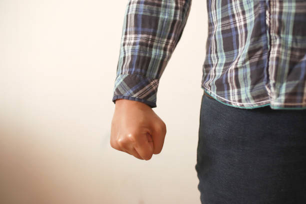 Angry person conceptual, clasped hands close up, ready to fight or punch, anonymous person over white background