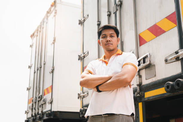 貨物トレーラートラックでクロスワンの腕を立っているアジアのトラック運転手の肖像画。 - flatbed truck truck truck driver heavy ストックフォトと画像