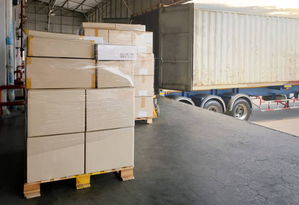istock Stack of cardboard on pallet rack. Cargo trailer truck parked loading at dock warehouse. Cargo shipment. Freight truck transportation. Logistics 1304837238