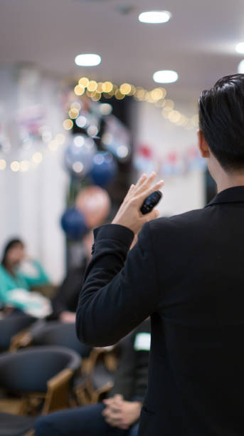 istock Presenter at corporate conference giving speech. Speaker giving lecture to business audience in seminar. Executive manager leading discussion in hall during company training event. Business photo. 1304841214