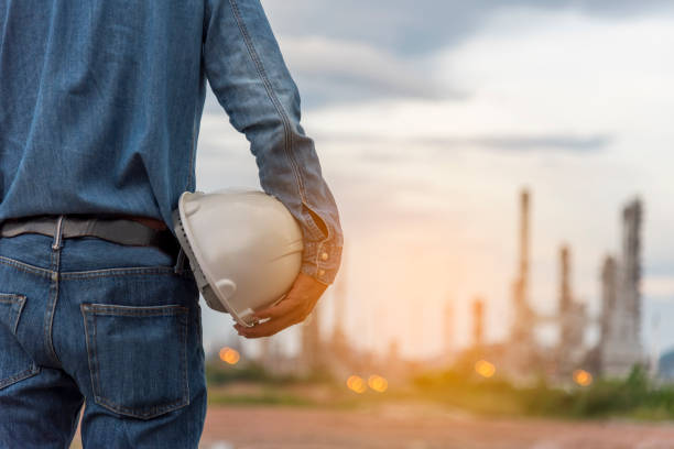 istock Engineer man hands holding hardhat white work helmet hard hat for Civil Construction Engineering. Construction engineer man in safety suit hold white work helmet hard hat on hands at Construction Site 1304843058