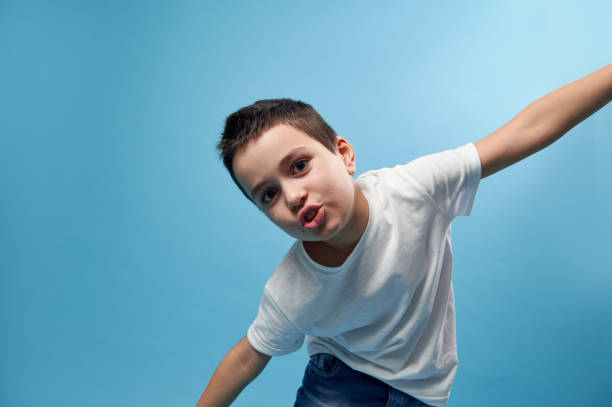 istock Boy imitates flight spread his arms like wings. Blue background copy space 1304844211