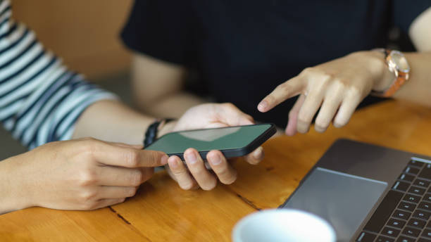 istock Two people working with smartphone on wooden table in workplace 1304844220