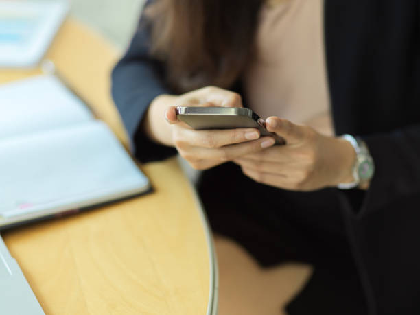 istock Close up view of businesswoman using smartphone while sitting at workplace 1304844285