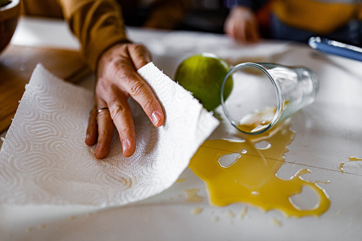 Close up of unrecognizable man cleaning spilled juice from the table.