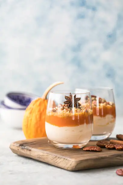 Autumn trifle dessert. Layered pumpkin parfait , pecan nut dessert in a glass, with autumn decorations.