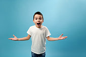 Shocked boy expressing surprise on camera. Facial emotions on blue background