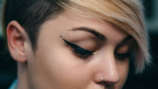 Close-up of a woman's face with perfect eyeliner and skin tone. Blondie with a piercing on her nose